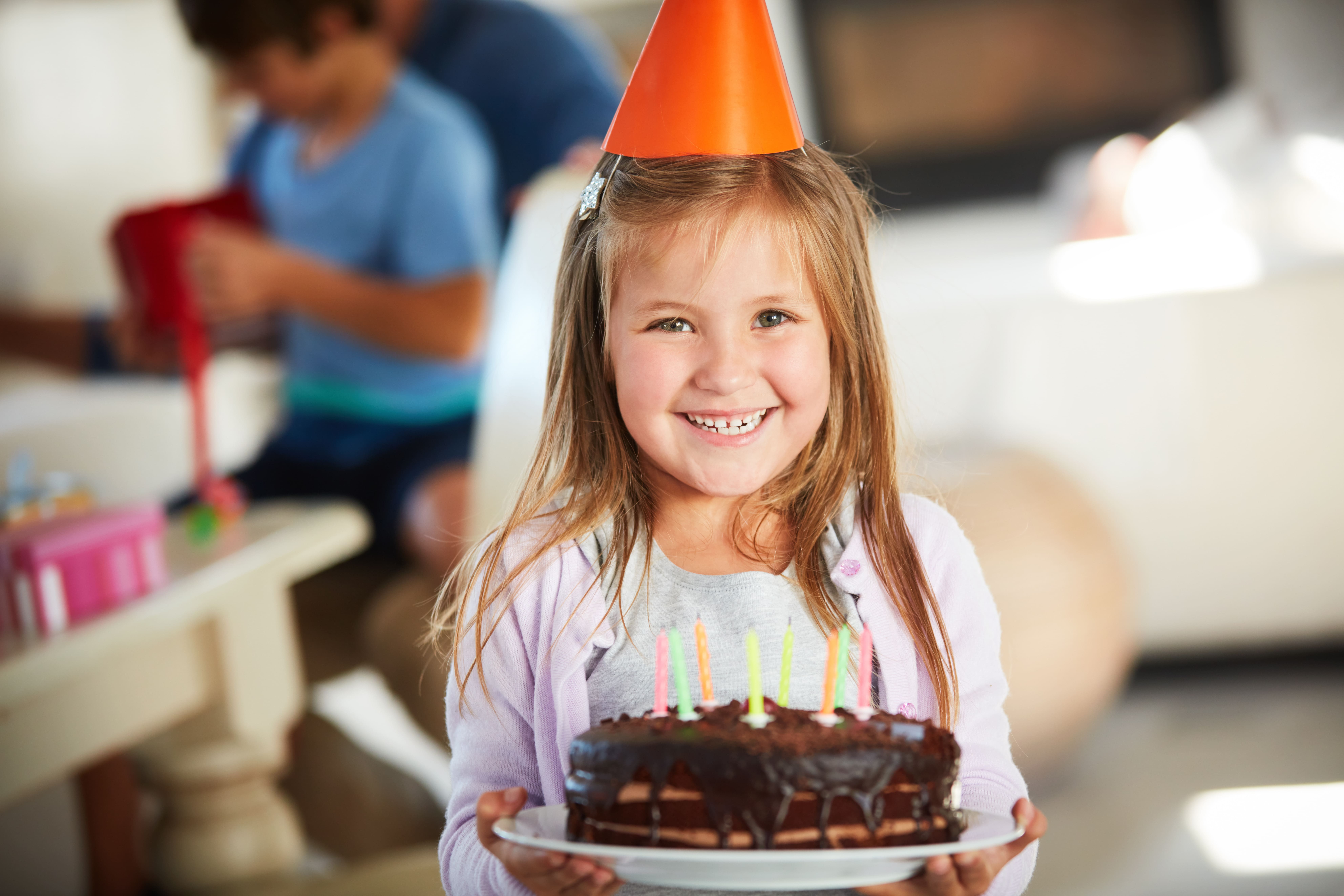 Smiling girl with birthday cake and party hat