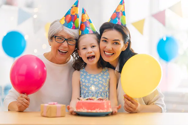 Grandmother, mother and daughter with a birthday cake and balloons