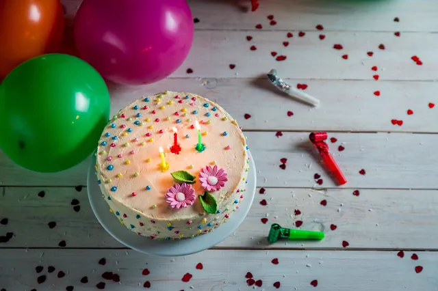 Sprinkle birthday cake on a wooden table with balloons
