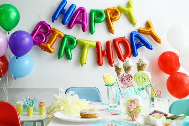 Happy Birthday foil balloon letters over a party table