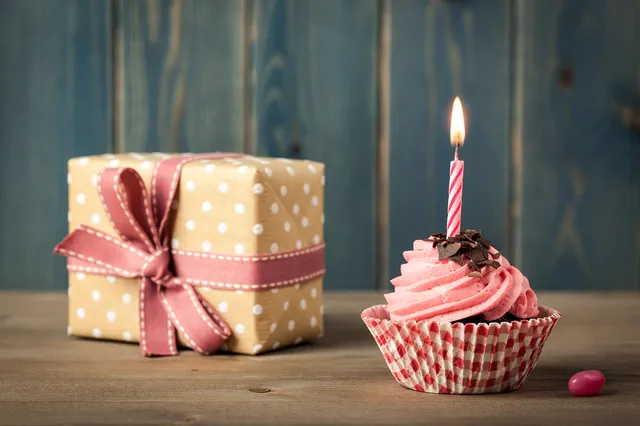 Polka-dot gift box and pink cupcake with a lit candle
