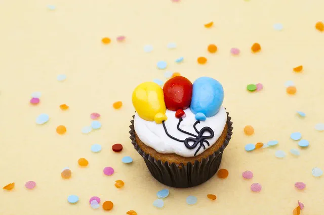 Cupcake topped with balloon decorations and confetti