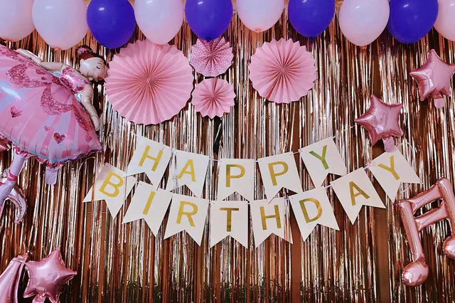 Happy Birthday banner with pink paper fans and balloons