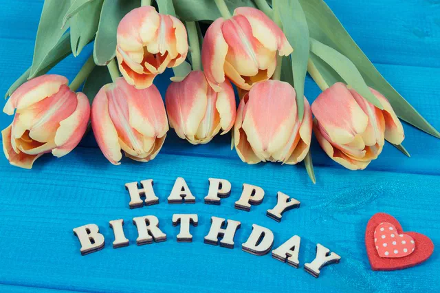 Pink tulips above wooden Happy Birthday letters