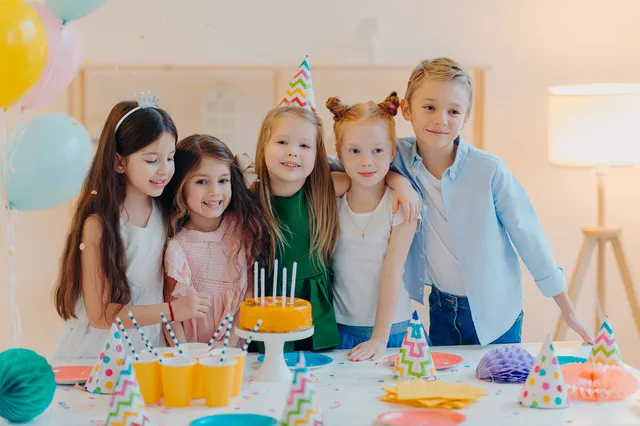 Children gathered at a birthday party table with cake