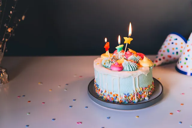 Drip birthday cake with lit candles and meringue kisses