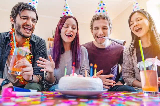Friends in party hats celebrating around a birthday cake