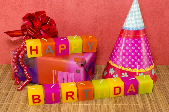 Happy Birthday letter candles with gifts and a party hat